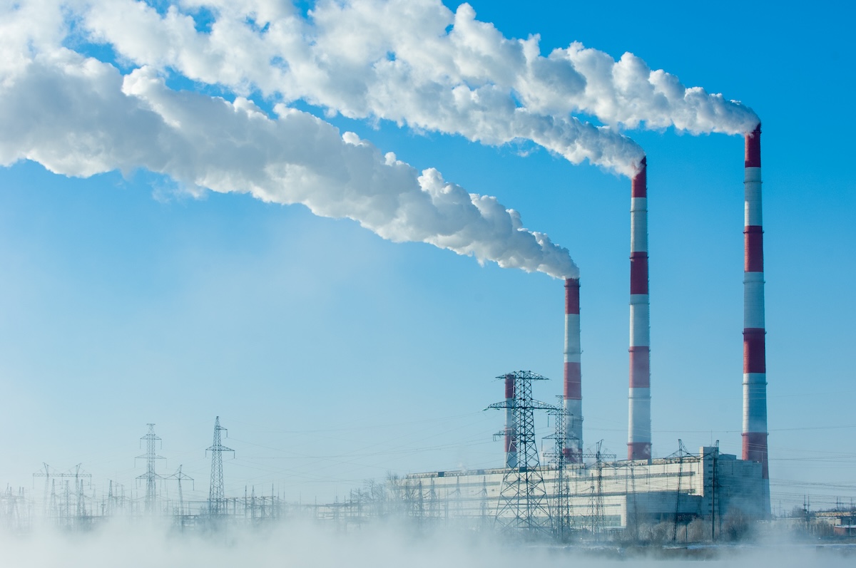 Kominy elektrociepłowni z parą wodną na tle zimowego nieba